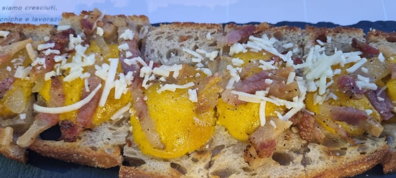 Close-up of a sandwich with crispy bacon, fried egg, and shredded cheese