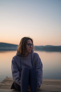 Woman sitting on the pier, closeup portrait, summer sunset