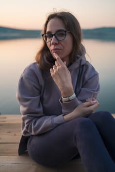 Woman sitting on the pier, closeup portrait, summer sunset