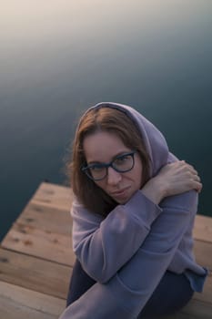 Woman sitting on the pier, closeup portrait, summer sunset