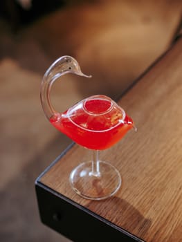 Cosmopolitan cocktail in swan bird glass, minimalistic aesthetic photo on bar counter edge. Popular alcoholic cosmopolitan cocktail made with vodka, triple sec, cranberry juice, lime juice. Bar menu