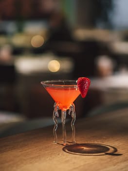 Strawberry margarita cocktail - minimalistic aesthetic photo on bar counter. Popular alcoholic cocktail strawberry margarita made with tequila, triple sec, strawberries in restaurant or pub interior