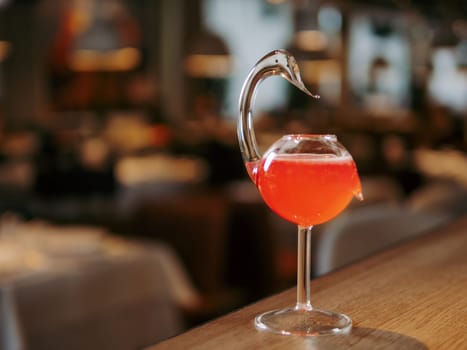 Cosmopolitan cocktail in swan bird glass on bar counter. Popular alcoholic cosmopolitan cocktail made with vodka, triple sec, cranberry juice, lime juice. Bar menu with copy space