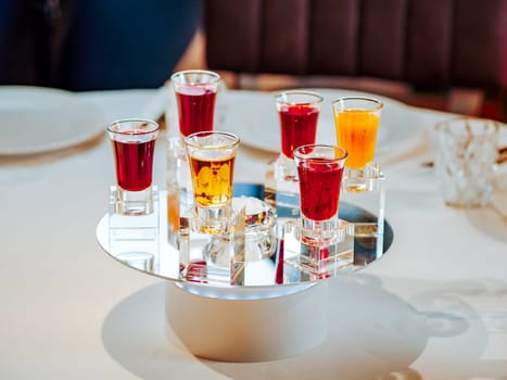 Set of colorful different bitters and liqueurs in shot glasses on restaurant table. Collection of shooters. Selection of natural berry alcoholic tinctures in glasses. Different bitters and liqueurs