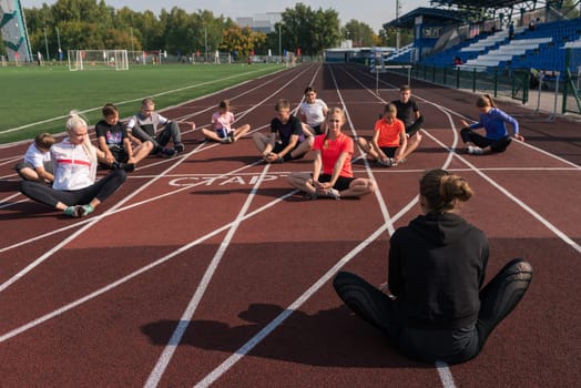 Female coach and group of children conducts a training session at the stadium. School gym trainings or athletics