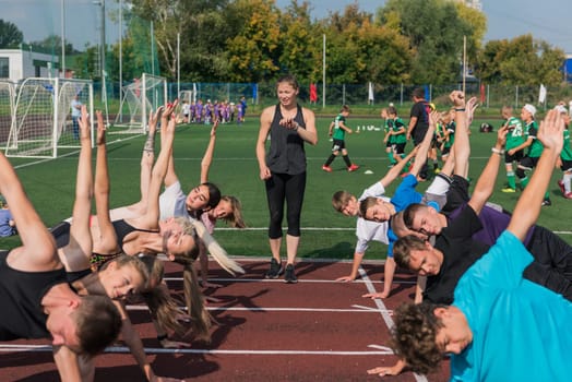 Female coach and group of children conducts a training session at the stadium. School gym trainings or athletics