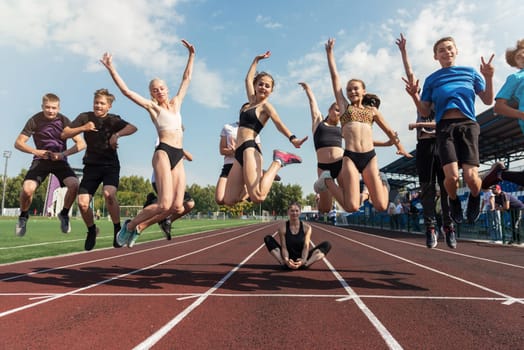 Female coach and group of jumping children at the stadium. School gym trainings or athletics