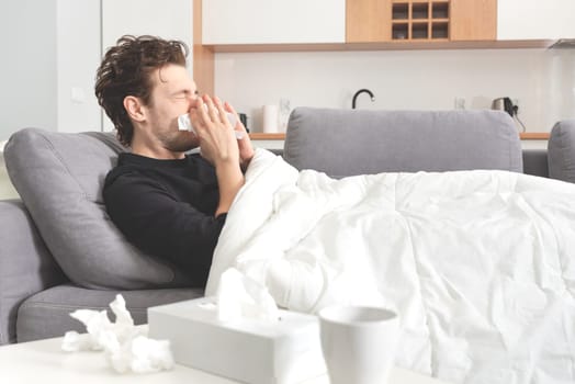 Sick man lying on sofa and blowing nose. Healthcare, disease concept