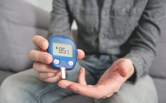 Young man measures blood sugar level. Diabetes using glucometer.