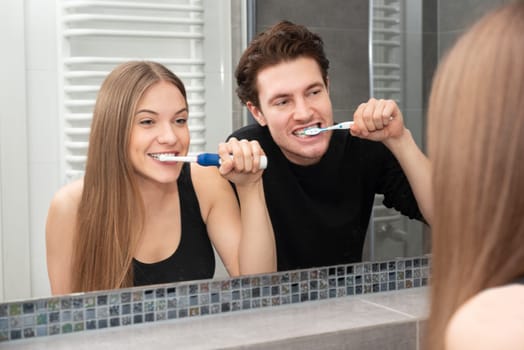 Couple brushing teeth in bathroom. Dental health concept