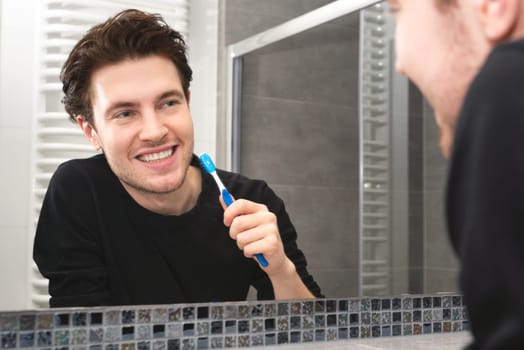 Man brushing teeth in bathroom. Dental health concept