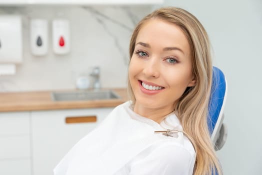Young smiling woman sitting on chair at dentist office. Dental care, healthy teeth.