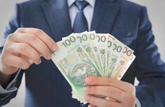 Man in a suit counts Polish banknotes. Government subsidies, aid programs for companies concept