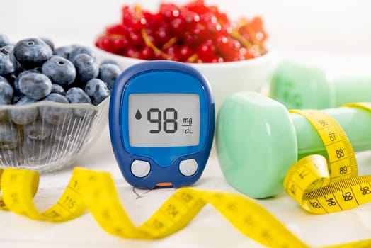 Glucometer with sugar level, diabetes concept. Fresh druits in bowl, diet and nutrition.