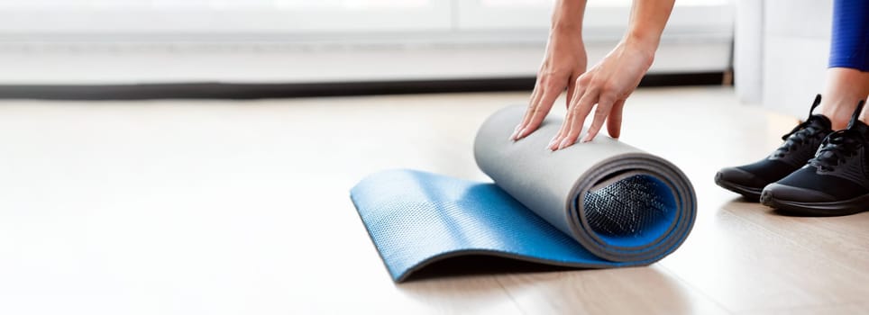Woman folding yoga mat, workout at home concept