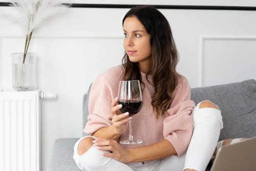 Woman sitting on couch, resting with glass of red wine