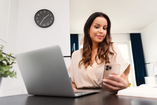 Attractive, beautiful woman using smartphone, working at home