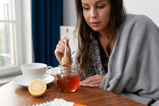 Sick woman putting some honey in her tea