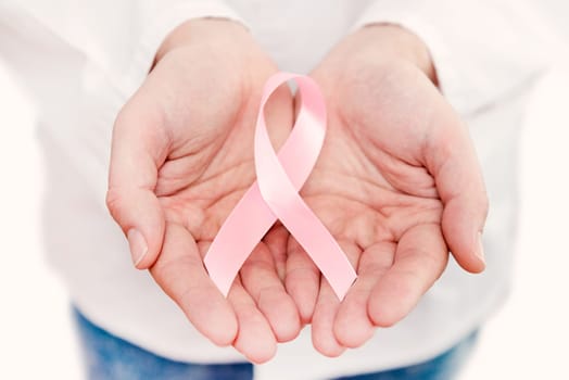 Hand holding pink breast cancer awareness ribbon with copy space