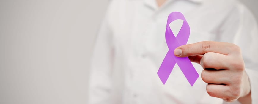 Man holding pancreatic cancer awareness ribbon. National cancer survivors month.