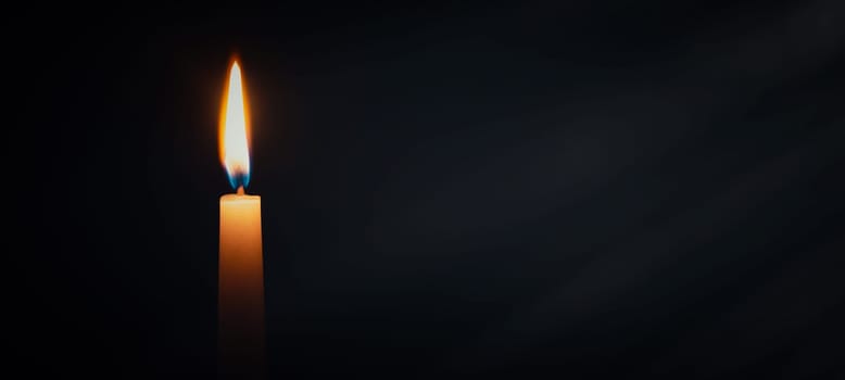 Candle burning in darkness over black background. Commemoration, necrology notice concept.