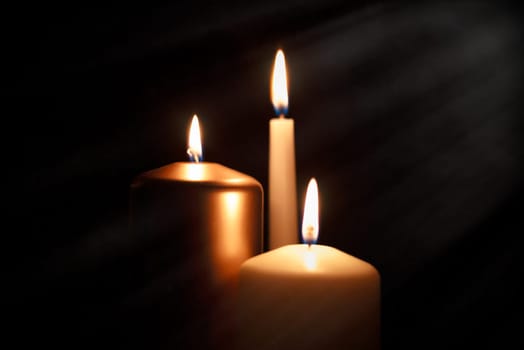 Funeral symbol with burning candle in darkness. Memorial composition