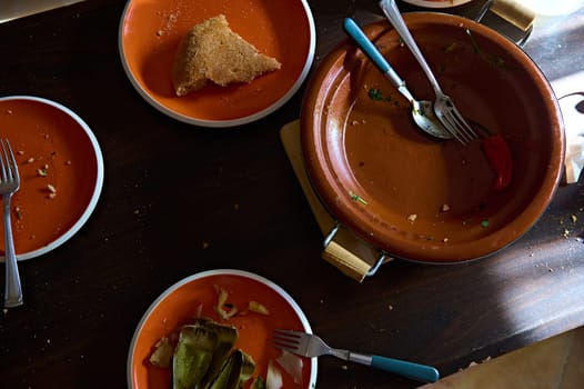 Dirty crockery and dirty clay plates and pots with the rest of unfinished lunch. Food blogging. Still life. View from above Leftover of lunch