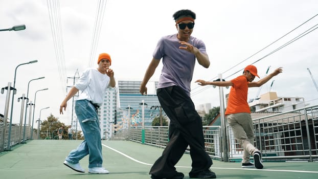 Group of professional break dancer dancing together or moving to hip hop music. Low angle camera of happy hipster team moving footstep and pose at camera. Crossing arm. Outdoor sport 2024. Sprightly.