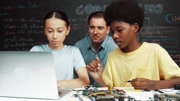 Caucasian teacher pointing at laptop while teaching about engineering code. Instructor working by using laptop while happy highschool student learning and studying programing system. Edification.