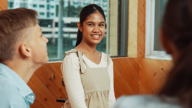 Young student smiling while listening other student in meeting or group discussion. Cute teenager talking about her experience and sharing to friends in mixed races. Creative education. Edification.