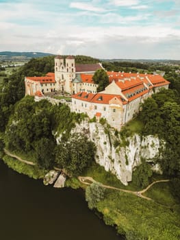 Aerial view of Benedictine abbey of Saints Peter and Paul in Tyniec, Poland. Old architecture of catholic monastery with towers and red roofs, religion and history landmark on rocks above water