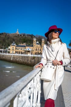 Stylish woman with maroon hat and white coat on Paseo de la Concha, San Sebastian