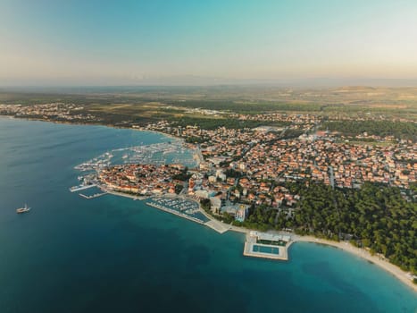 Biograd na Moru, marina aerial view with beach, sailing boats and luxury yachts in port. Historic Old Town architecture, summer clear sky and blue waters of Adriatic Sea in Dalmatia region of Croatia