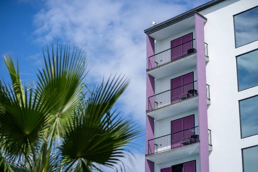 Modern residential building with empty balconies, palm tree leaves and blue sky of Biograd na Moru in Croatia