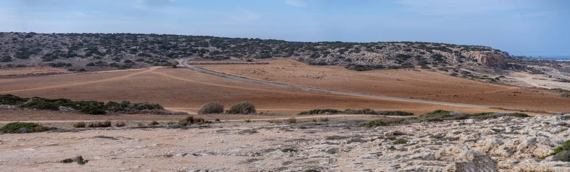 Panoramic landscape with winding asphalt road through hills and rocky lands in Cape Greco National Park, Cyprus