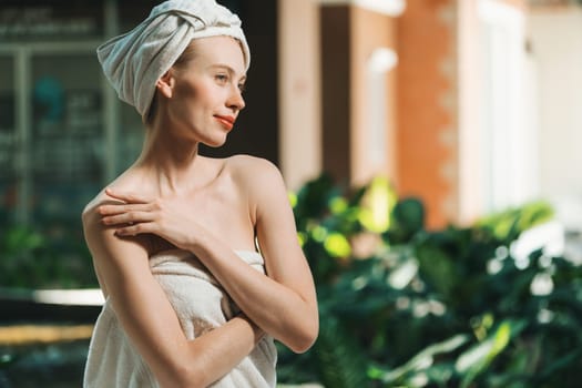Attractive Caucasian woman with beautiful skin in white towel standing with confidence surrounded by natural environment at outdoor. Pretty girl standing while waiting for massage. Tranquility.