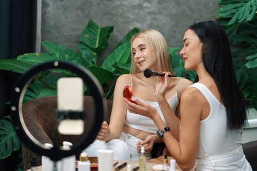 Two beautiful content creator making natural beauty and cosmetic tutorial on green plant garden video. Beauty blogger showing how to beauty care to social medial audience using selfie stick . Blithe