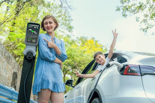 Family road trip vacation with electric vehicle, mother and son recharge EV car with green and clean energy. Nature and travel with eco-friendly car for sustainable environment. Perpetual