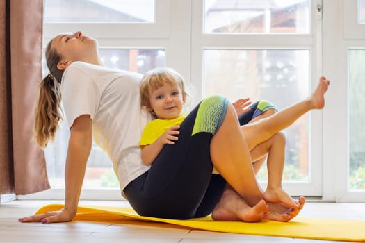 Mother and son family doing fitness, yoga, exercise on a yoga mat at home.