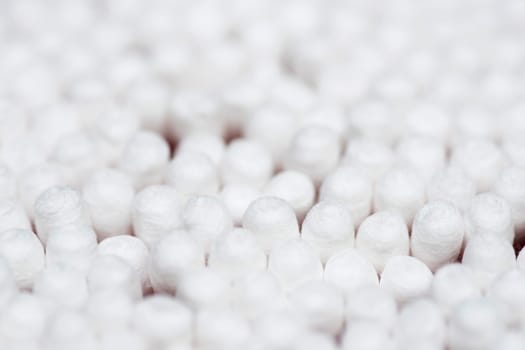 Many white cotton sticks. Round container with cotton buds.