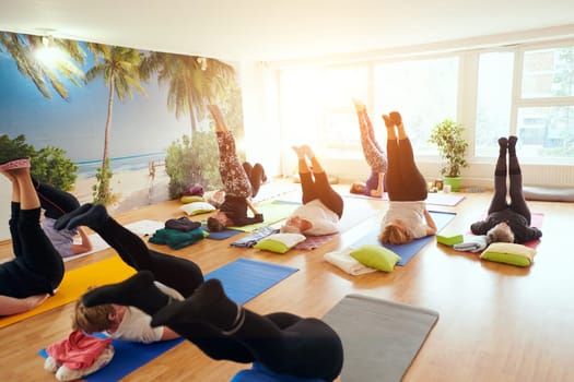 A group of senior women engage in various yoga exercises, including neck, back, and leg stretches, under the guidance of a trainer in a sunlit space, promoting well-being and harmony.