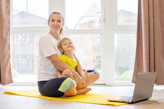 Mother and son family doing fitness, yoga, exercise on a yoga mat at home.