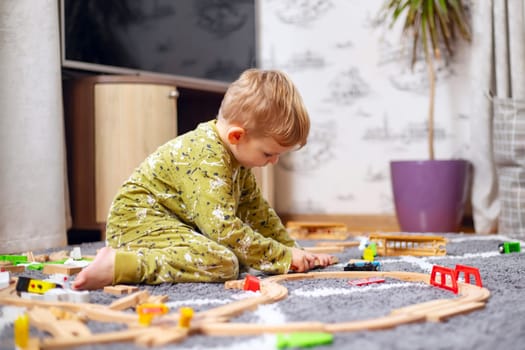 Child playing with developmental toys. Baby playing with toy railroad, trains and cars on the floor. Children at home or in kindergarten