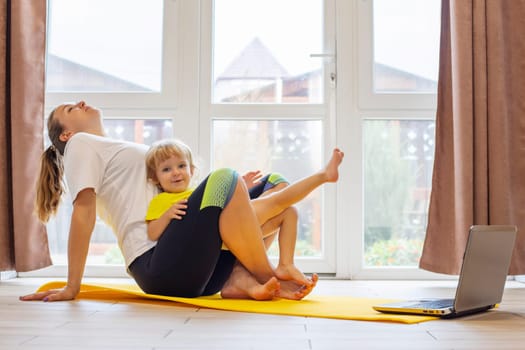 Mother and son family doing fitness, yoga, exercise on a yoga mat at home.