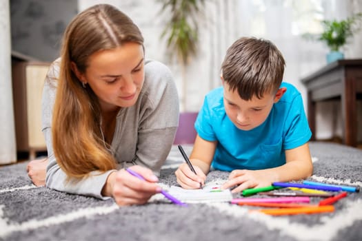 Happy family playing together at home on floor. Mother and her son painting together