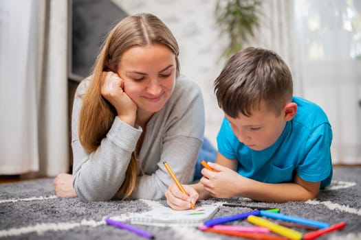 Happy family playing together at home on floor. Mother and her son painting together