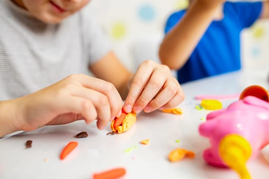 Kids playing with play dough. Cute children sitting at the table and plays with playdough. Creative leisure activity concept