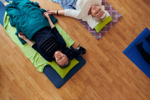 Top view of group of senior women engage in various yoga exercises, including neck, back, and leg stretches, under the guidance of a trainer in a sunlit space, promoting well-being and harmony.