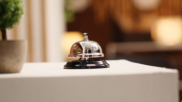 Extreme close up of concierge bell next to mini plant on cozy hotel lounge check in desk. Elegant service bell on modern stylish hospitality industry resort reception counter