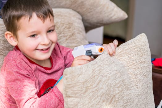 Cute boy is playing with toy guns at home. Cute little preschool kid boy is playing with gun at home, nursery or kindergarten.